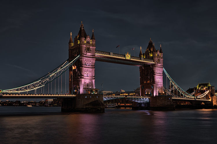 Illuminated tower bridge over thames river against sky at night
