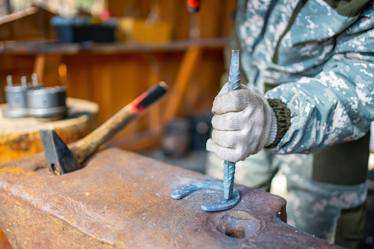 Midsection of blacksmith working in workshop