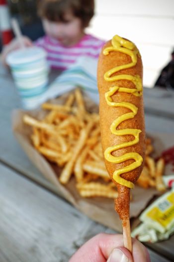 Cropped image of person holding corn dog