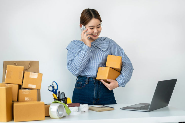 Side view of young woman using laptop while sitting against white background