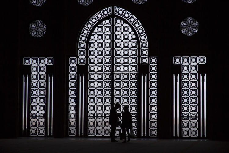 Man and woman standing at entrance gate of mosque hassan ii during night