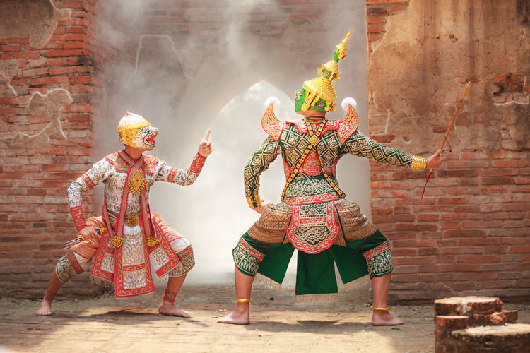 Male performers wearing traditional clothing while acting on stage