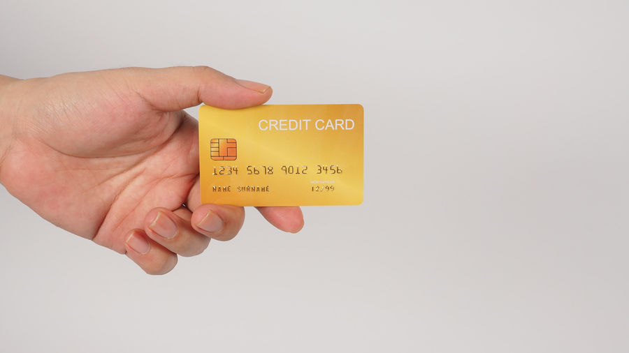 Cropped hand holding paper currency against white background