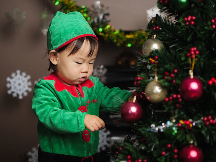 Cute girl wearing costume standing by christmas tree at home