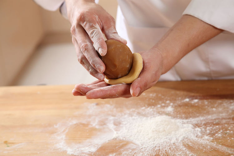 Midsection of woman preparing sweet baking food with dough at kitchen counter