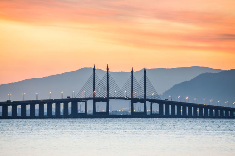 Bridge over bay against sky during sunset