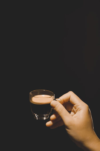 Midsection of person holding drink against black background