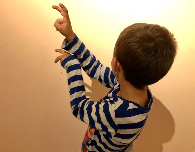 Rear view of boy standing against wall