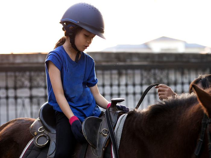 Asian school kid riding or practicing horse at horse ranch.