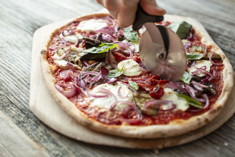 Close-up of pizza on table being cut