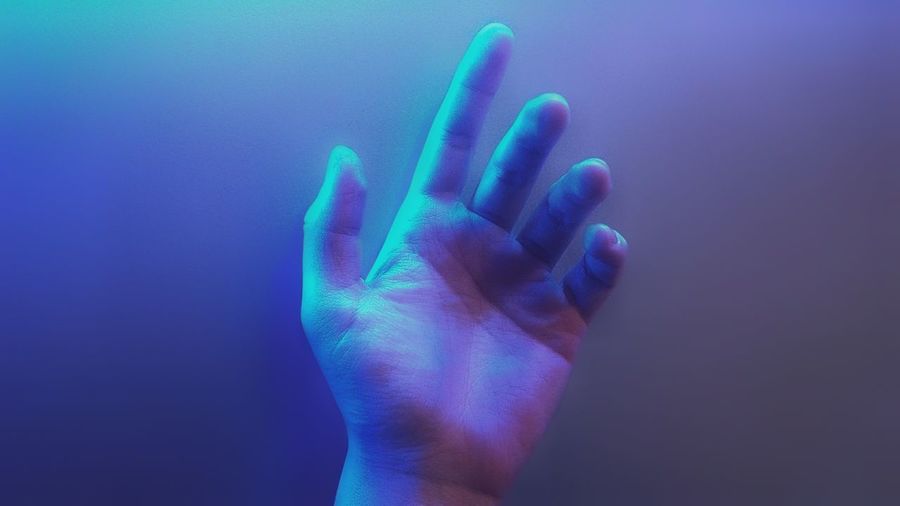 Close-up of human hand against blue background