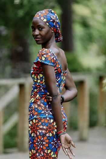 Back portrait young woman looking wearing african dress by garden