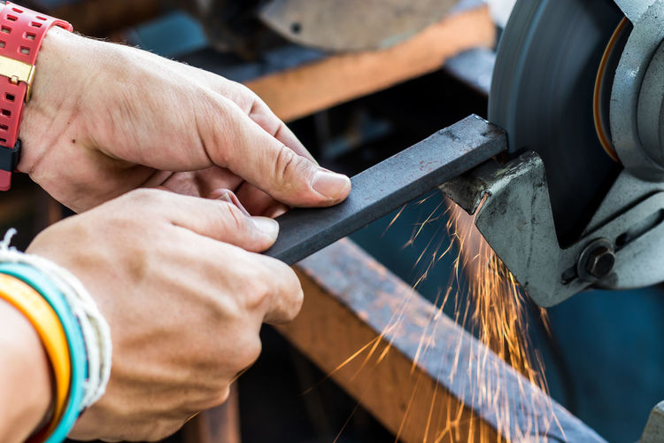 Cropped hands of manual worker working in factory