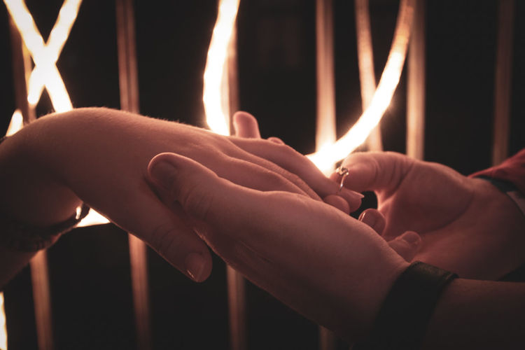 Close-up of couple holding hands at night