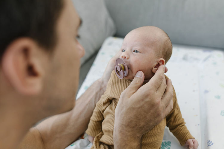 Man holding baby with pacifier at home