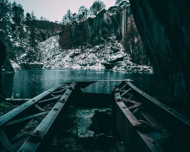 Abandoned boat on lake against rocky mountains