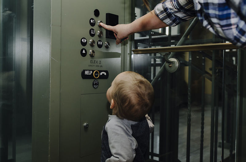 Son looking at mother pressing elevator button