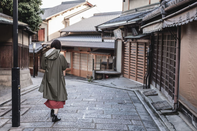 Rear view of woman walking on street amidst buildings