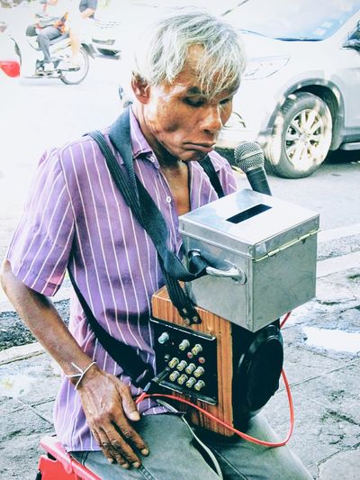 Blind street musician with speaker sitting on footpath