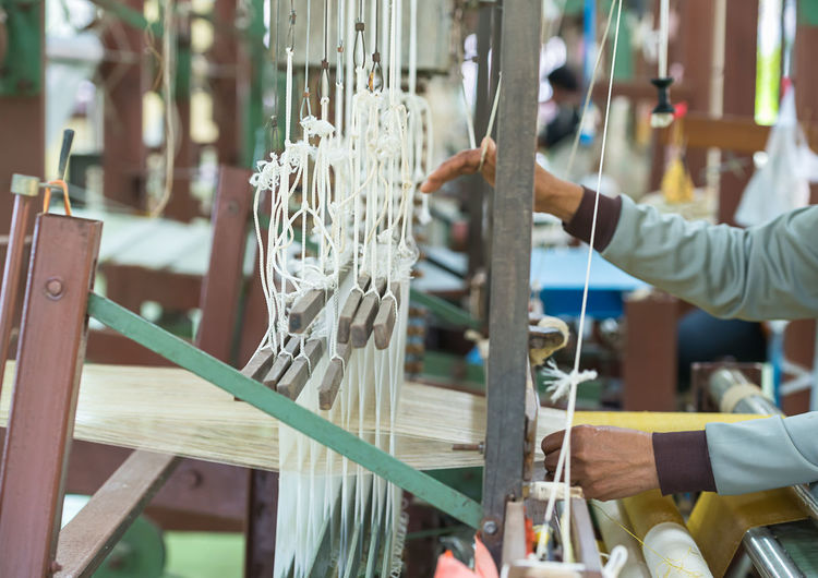 Cropped hands of woman using loom