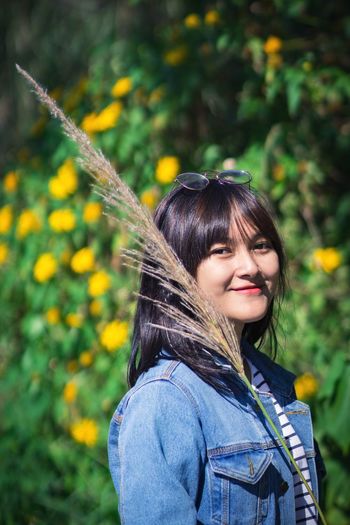 Portrait of smiling young woman standing against tree