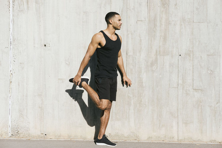 Full length of african american male athlete stretching legs person