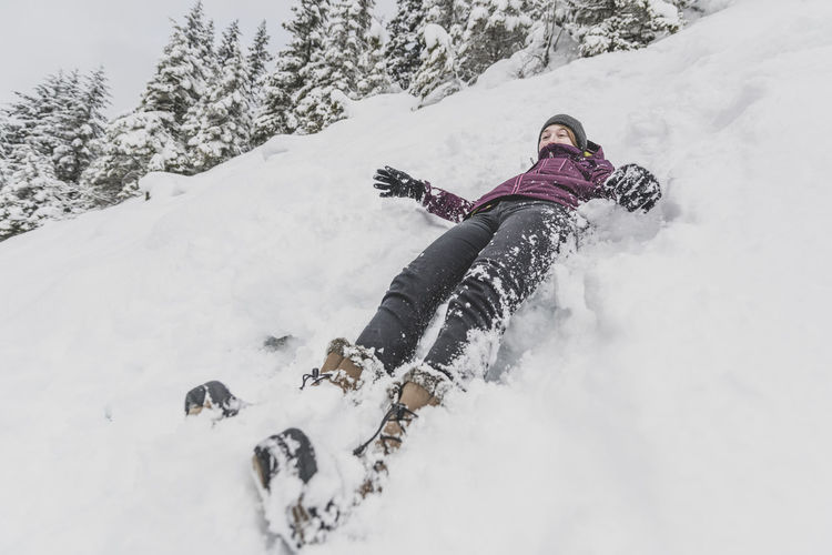 Young woman with hat sliding fast in the snow downhill funny face