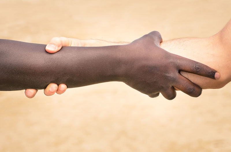 Close-up of people holding hands on sand