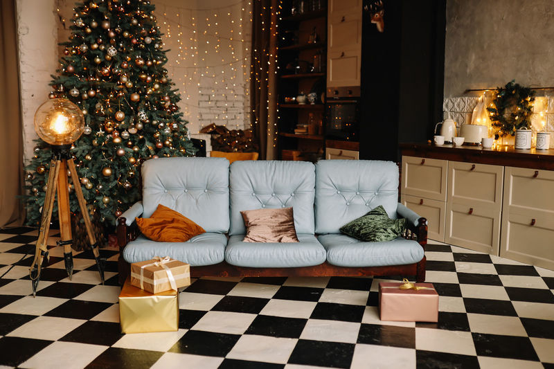 Christmas decorated interior of a loft style room in a cozy house, sofa and gift boxes 