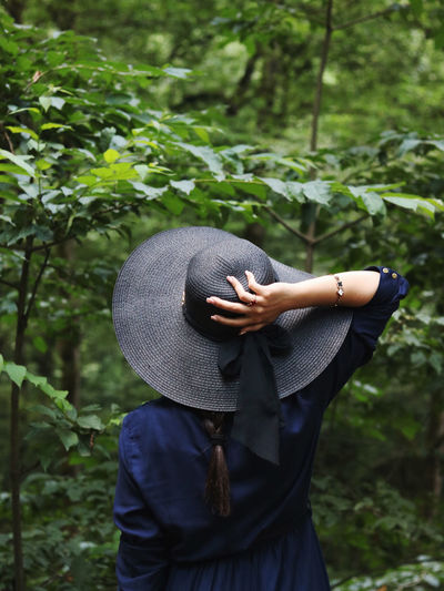 Midsection of woman wearing hat standing by tree