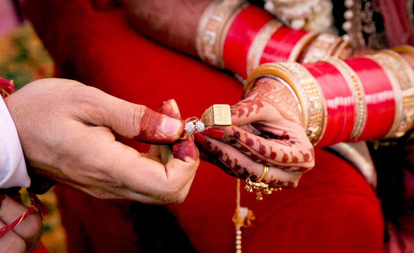 Midsection of bride and groom holding rings during wedding ceremony