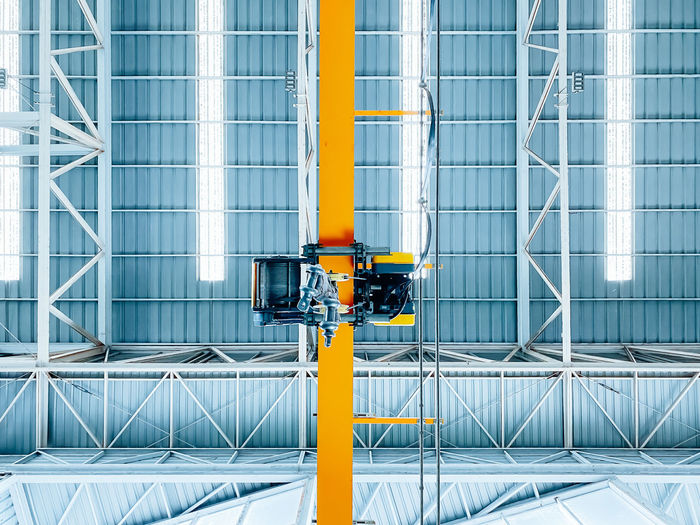 Overhead crane inside factory building, industrial background.