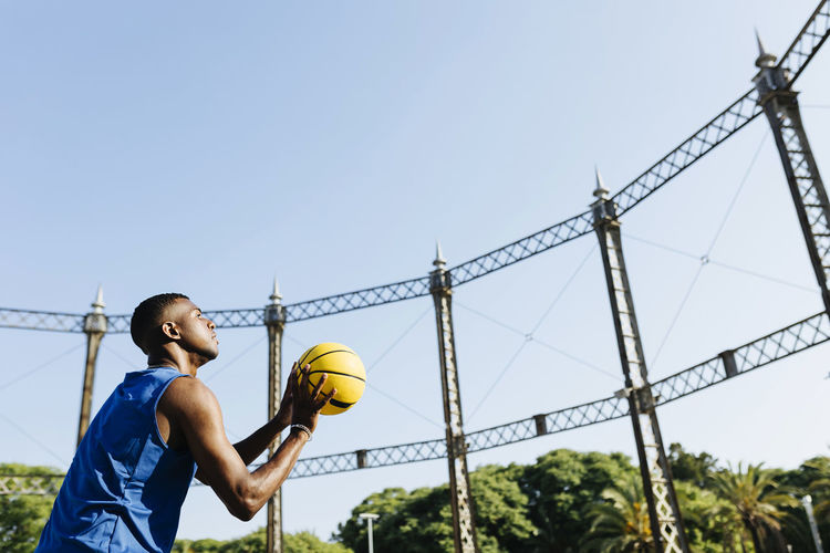 Young man playing basketball at sports court