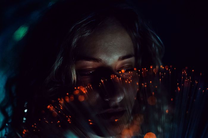 Close-up of thoughtful woman with fiber optic at night 