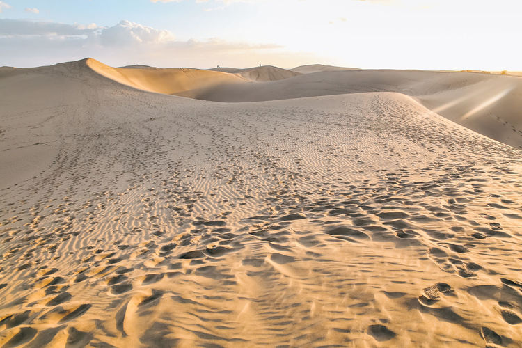 Sand dune with human footprints in desert against sly