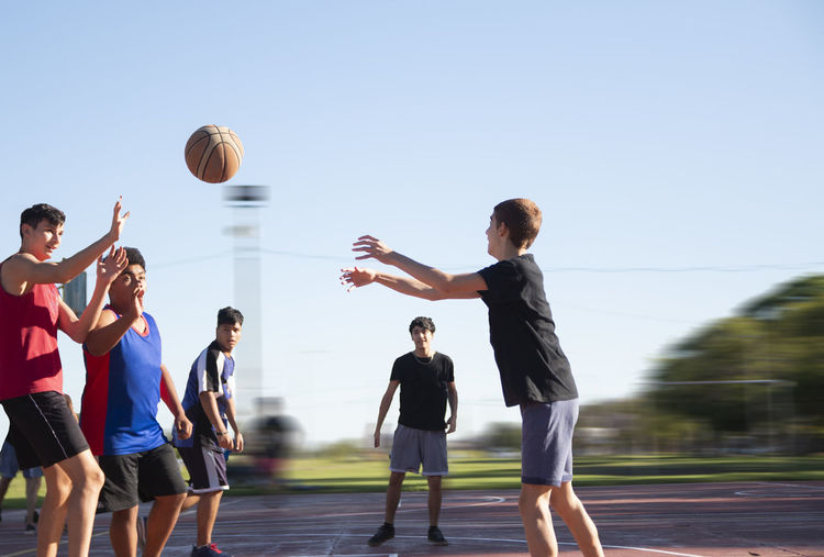 Group of teenagers playing street basketball