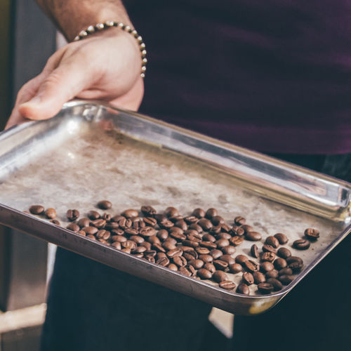 Man holding tray with coffe beans