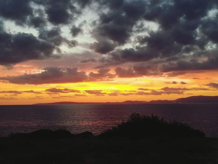 Scenic view of sea against dramatic sky during sunset