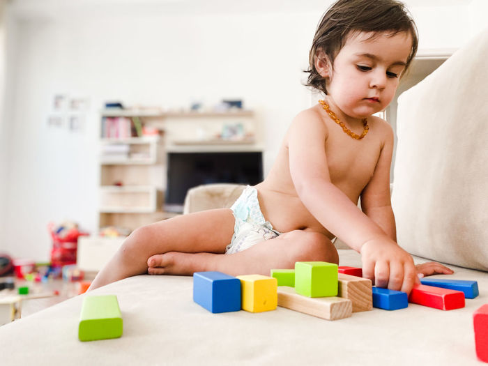 A toddler boy playing with wooden toy blocks at home