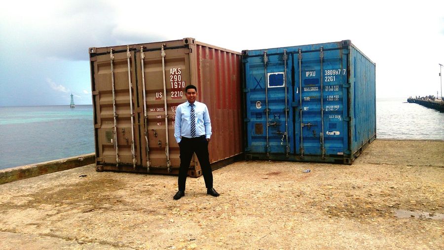 Full length of businessman standing at dock against containers