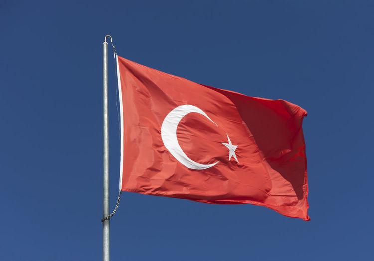 Low angle view of turkish flag against clear blue sky