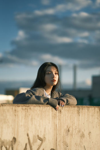 Portrait of an aisan young woman looking away against the sky at rooftop