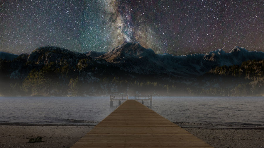 Pier over lake against sky at night