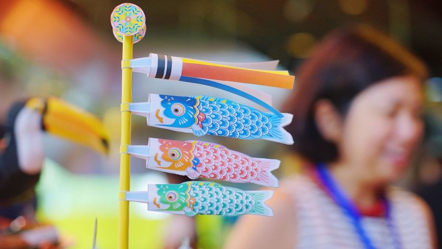 Close-up of colorful paper koinobori by woman during traditional festival