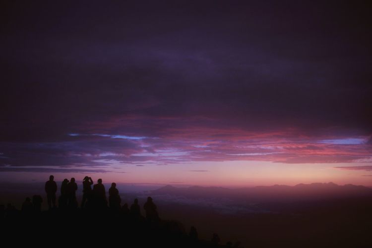 Silhouette people standing on mountain against sky during sunset