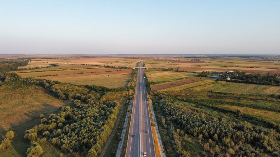 Panoramic shot of road amidst field against clear sky