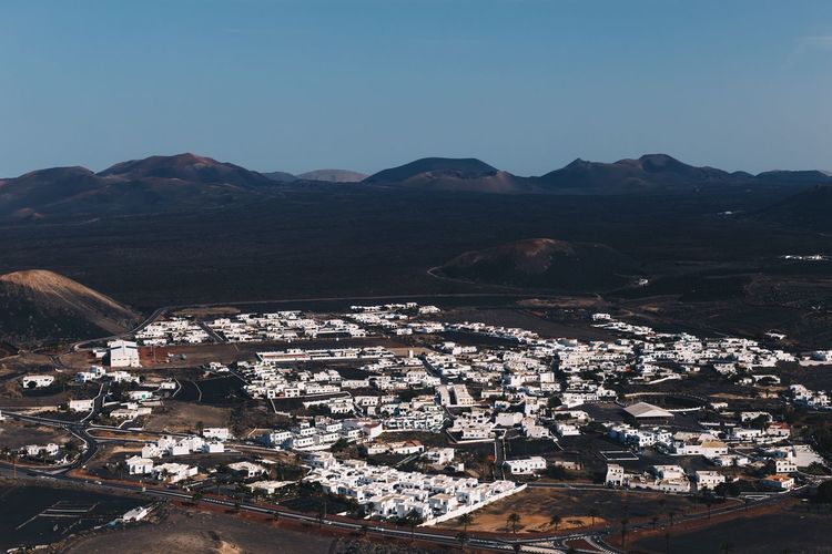 Aerial view of townscape by mountains against clear sky