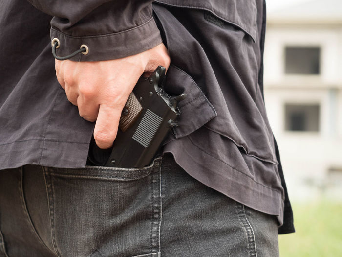 Midsection of thief removing gun from back pocket