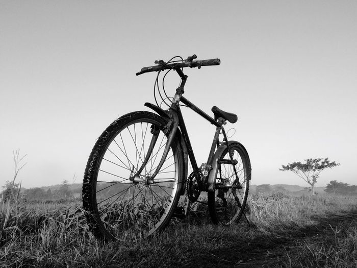 Bicycle on field against clear sky