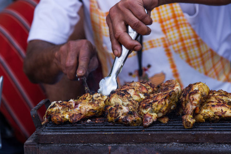 Cropped image of man grilling chicken at market stall